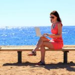 freelancer works from the beach with their earnings