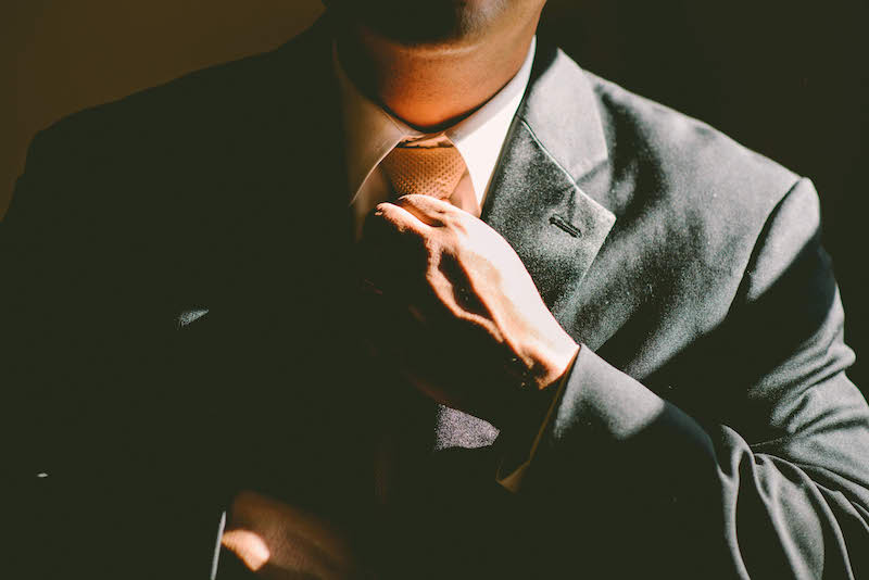 man fixing his tie in a suit